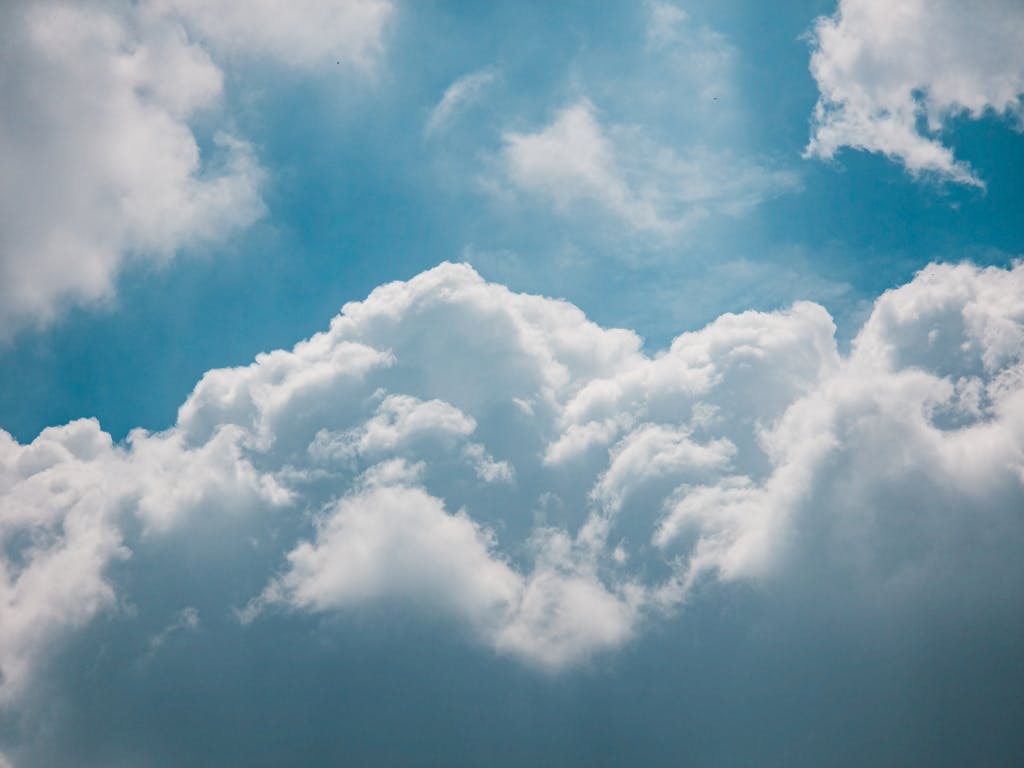 Serene view of fluffy white clouds in a bright blue sky, offering a peaceful atmosphere.